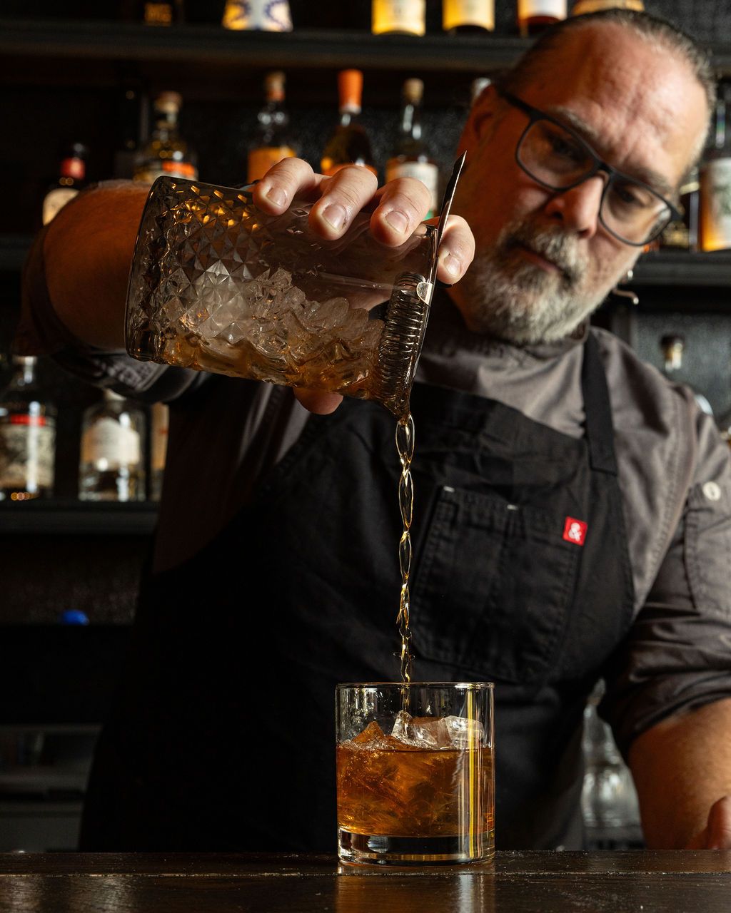 Bartender pouring a cocktail behind the Five & Dime bar